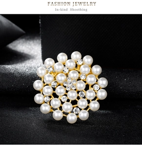 Détail d'une élégante broche flocon dorée ornée de perles blanches et de cristaux brillants
