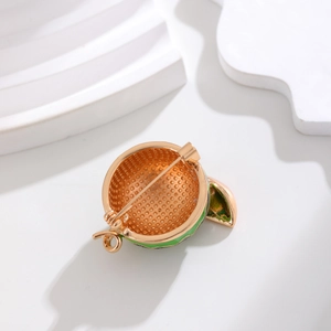 Minimalist enamel watermelon brooch in gold finish displayed on white creative props