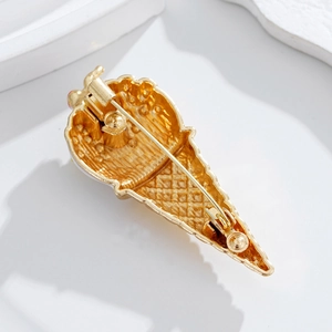 Broche crème glacée dorée avec accents diamants et fermoir épingle sur fond blanc