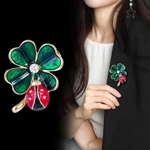 Broche trèfle à quatre feuilles en émail vert avec coccinelle sur fond noir élégant