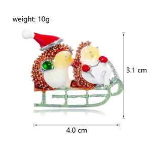 Broche hérisson de Noël sur traîneau vert en émail avec bonnet rouge dimensions 4,0x3,1cm