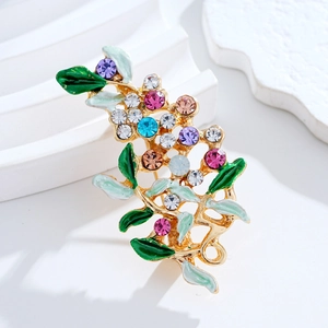 Elegant floral brooch with colorful crystals and green enamel leaves on a gold base