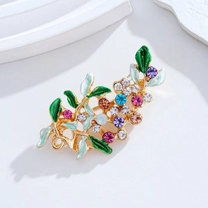Elegant floral brooch with colorful crystals and green leaf details on white background