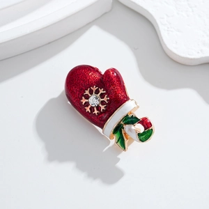 Detailed close-up of a red enamel Christmas glove brooch with a gold snowflake and rhinestone