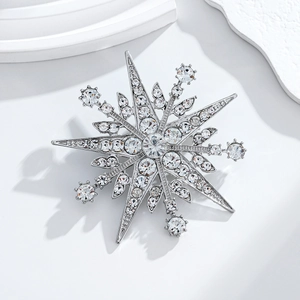 Elegant silver starburst brooch with sparkling rhinestones on a white podium