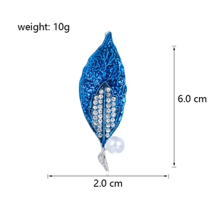 Elegant blue enamel leaf brooch with rhinestones and pearl detail on white background