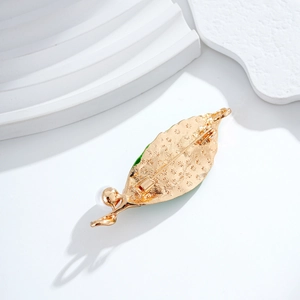 Elegant gold double leaf brooch with white pearl detail on minimalist stone background