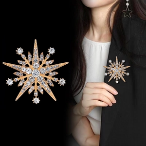 Sparkling starburst brooch with crystals shown as product shot and on black blazer