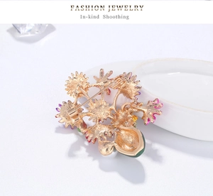 Detail view of the floral brooch back showing the safety pin clasp and golden alloy finish