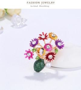 Detail of colorful enamel daisy brooch with rhinestones, pearl, and bird motif