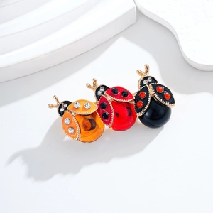 Tre spille a forma di coccinella colorate in rosso, arancio e nero con strass lucidi
