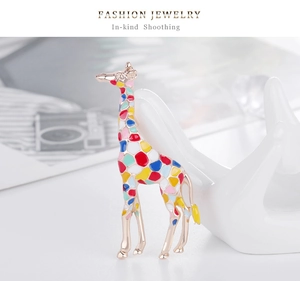 Détail d'une broche girafe en émail coloré avec base dorée sur un support à bijoux