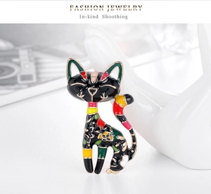 Detail of colorful enamel cat brooch with floral patterns on white jewelry stand
