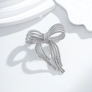 Elegant silver bow brooch with twisted rope texture on a minimalist white background