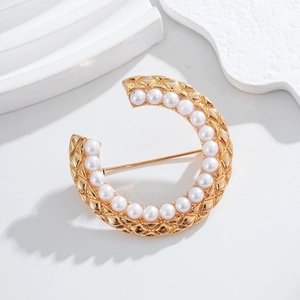 Elegant gold C-shaped brooch with quilted metal texture and white pearl lining