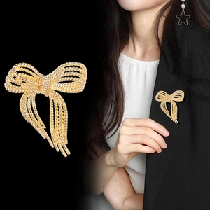 Elegant gold beaded bow brooch with long tassels shown on professional attire