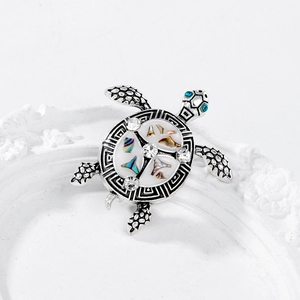 Detailed close-up of a vintage silver turtle brooch with abalone shell and rhinestones