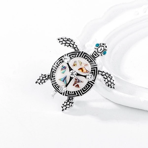 Detailed close-up of a silver turtle brooch with white enamel and colorful shell inlay