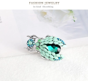 Macro shot of vintage beetle brooch with emerald gemstone and green crystal wings