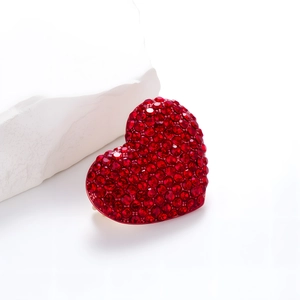 Elegant red heart brooch with crystal pavé setting against a white stone display