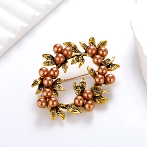 Macro view of vintage wreath brooch with bronze pearls and crystals on gold leaves
