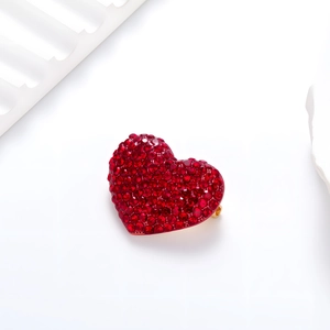 Close-up of heart-shaped brooch with vibrant red crystals on gold-tone metal base