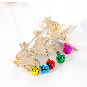 Rear view of Christmas tree brooch with colorful bells on white magazine background