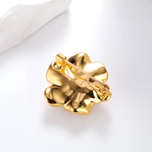 Luxurious camellia flower brooch with gold finish and pearl detail in a front view