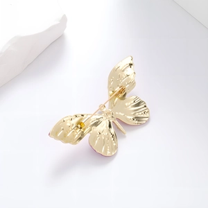 Eleganter goldener Schmetterlings-Anstecker mit Emaille-Flügeln auf weißem Hintergrund