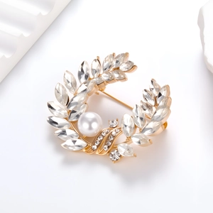 Broche couronne de feuilles dorées avec cristaux brillants et une perle blanche centrale