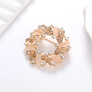 Broche couronne dorée avec pierre œil de chat rose et cristaux brillants sur fond blanc