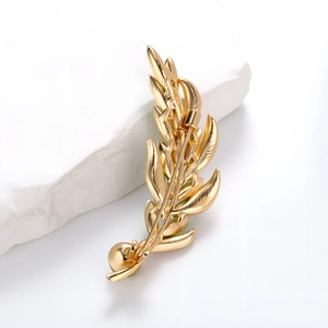 Elegant gold wheat ear brooch pin with crystal glass details on a white marble background