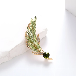 Elegant gold wheat brooch with green crystals and white diamonds on white stone base