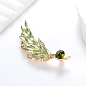 Macro detail of wheat ear brooch with green crystals and gold metal finish