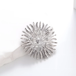 Broche soleil argentée élégante avec strass et épingle sécurisée sur fond blanc épuré