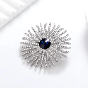 Détail macro de la broche tournesol avec cristal bleu et strass scintillants sur métal