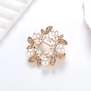 Elegant gold flower wreath brooch with white pearls and sparkling crystals on white base