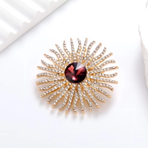 Détail macro d'une broche tournesol avec gemme rouge foncé et pétales en cristal
