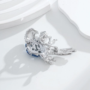 Broche perroquet argentée avec pierres bleues et perle, vue arrière avec épingle de sûreté