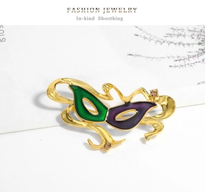 Dettaglio della spilla a maschera in smalto verde e viola con strass color champagne