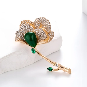 Detailed view of Ginkgo leaf brooch with green drop gemstone and white rhinestones