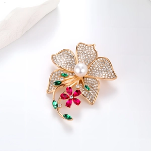 Macro detail of a flower brooch with white crystals, pearl center and red gemstone petals