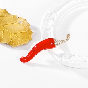 Detalle de broche de chile en esmalte rojo con brillantes sobre una bandeja