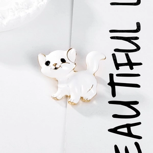 Détail d'une broche chat en émail blanc avec bordure dorée sur un fond minimaliste