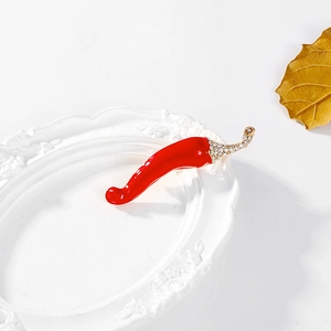 Detalle del broche de chile rojo con tallo dorado e incrustaciones de pedrería