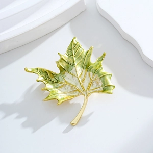 Elegant maple leaf brooch in gold metal with gradient green enamel on white stone base