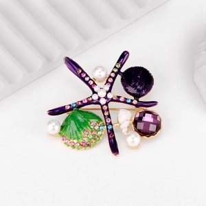 Macro detail of starfish brooch with purple enamel pearls and colorful rhinestones