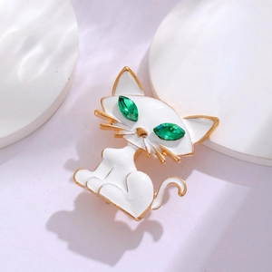 Elegante spilla a gatto in smalto bianco con occhi in gemme verdi e finiture dorate
