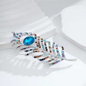 Elegant silver feather brooch with colorful rhinestones and a large blue oval gemstone