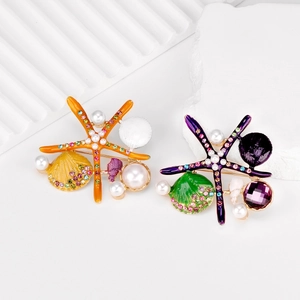 Detail of colorful enamel starfish and shell brooches with inlaid rhinestones and pearls